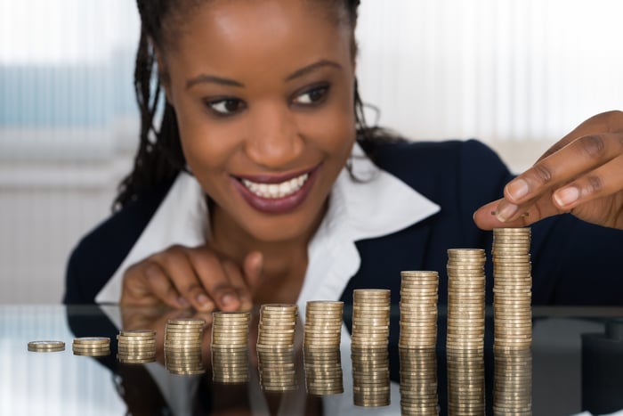 A woman looks at a row of coin stacks, which increase in height.