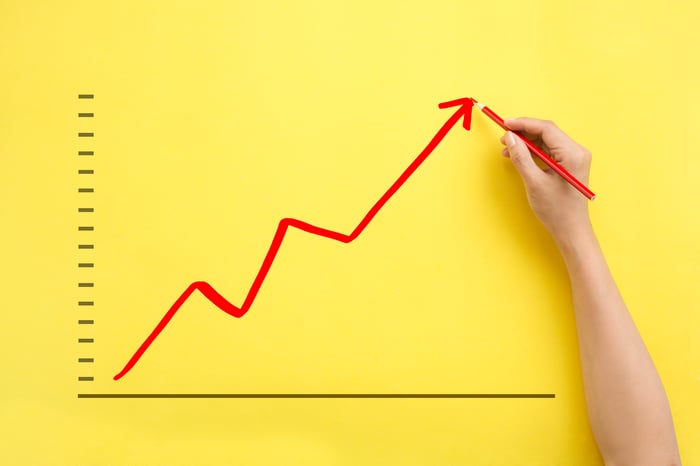 Hand drawing a rising red stock arrow representing a stock going up on yellow background