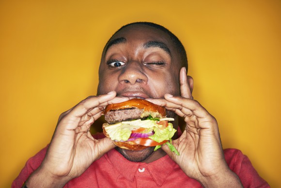 A man taking a bite out of a hamburger.
