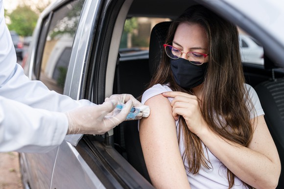 Woman receiving flu vaccine at drive-thru site.