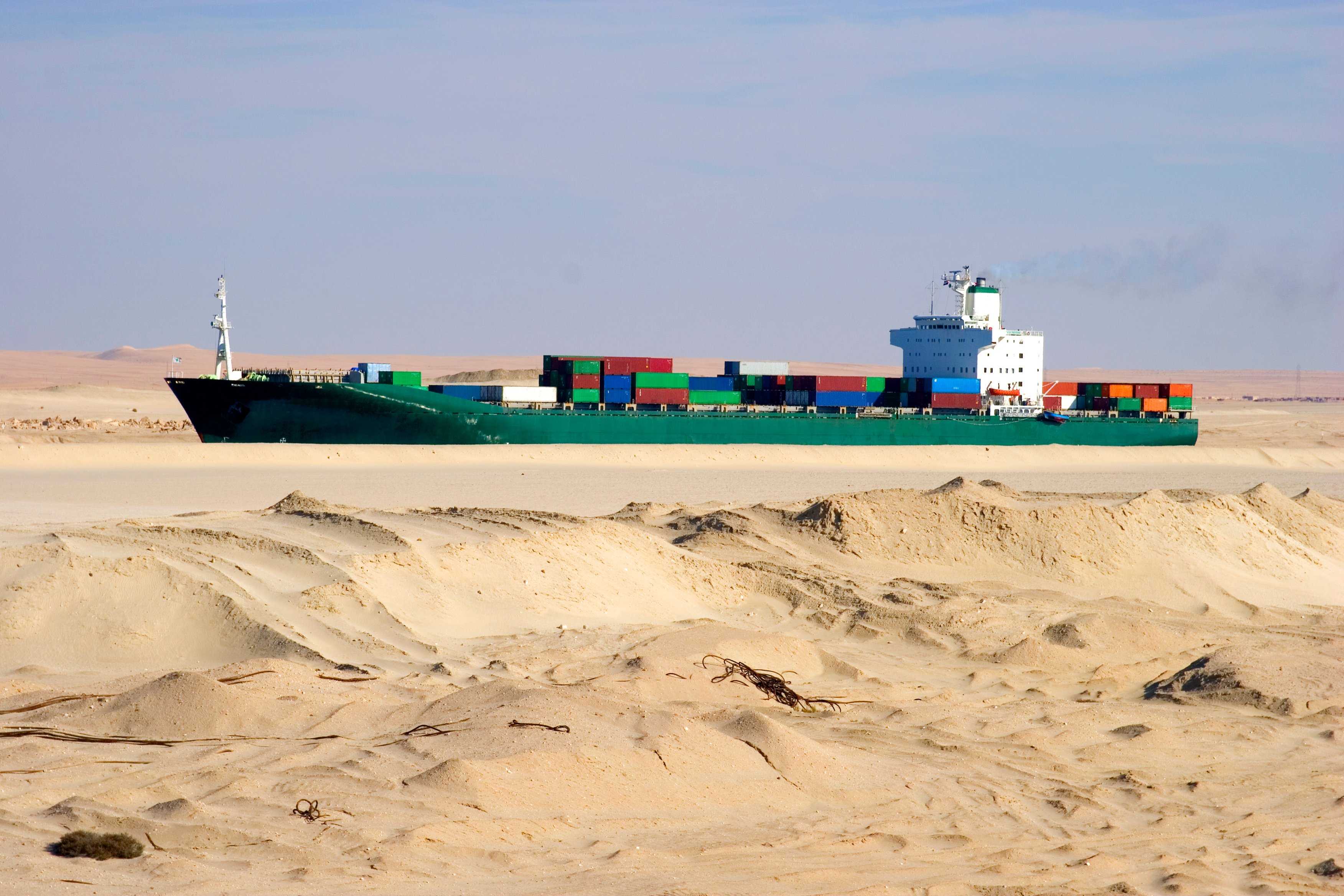 Container ship looks like it's in a desert but actually transits the Suez Canal
