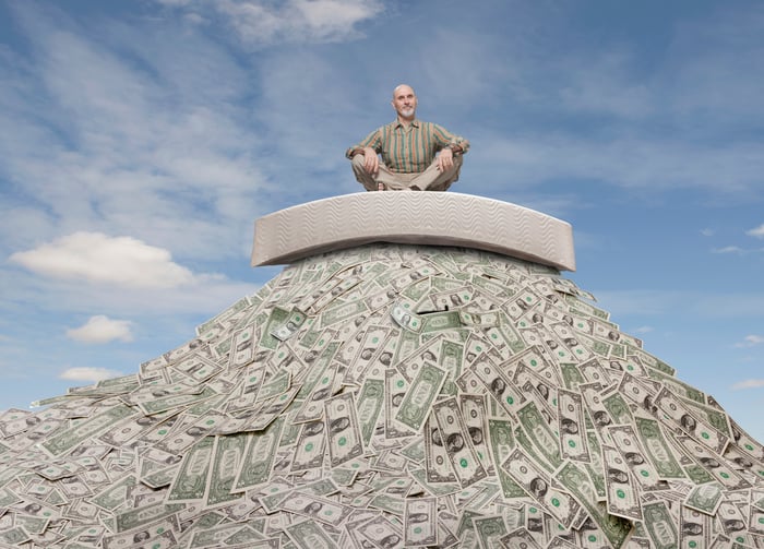 Retiree sitting on top of a large pile of cash