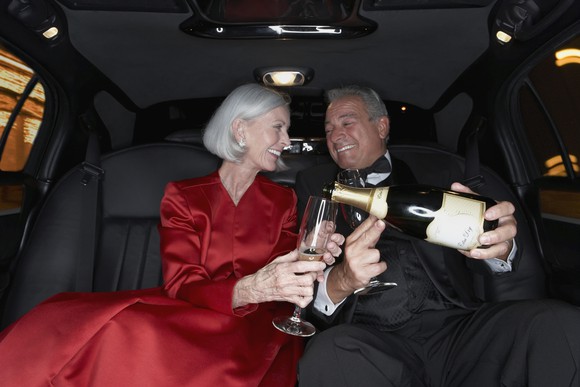 A senior couple drinks Champagne in a limousine.