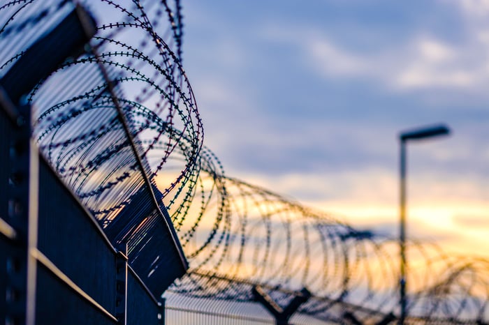 Barbed wire wrapped around the top of a fence.