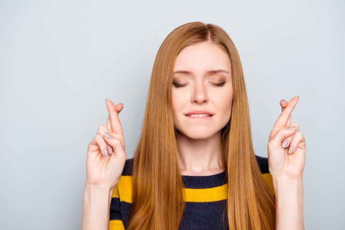 Woman with eyes closed and fingers crossed