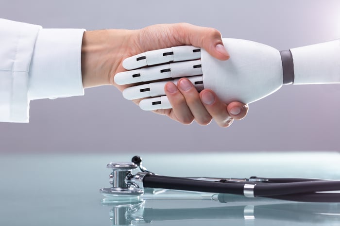 A human hand is shaking hands with a robot hand.