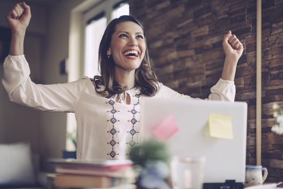Woman cheering in front of laptop