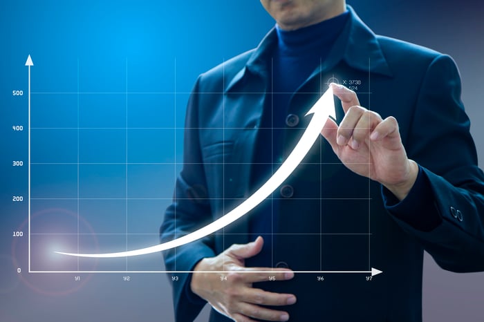 A businessman draws an exponential growth curve on a line graph.