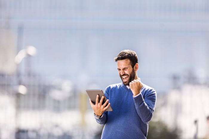 Man holding tablet and smiling in celebration