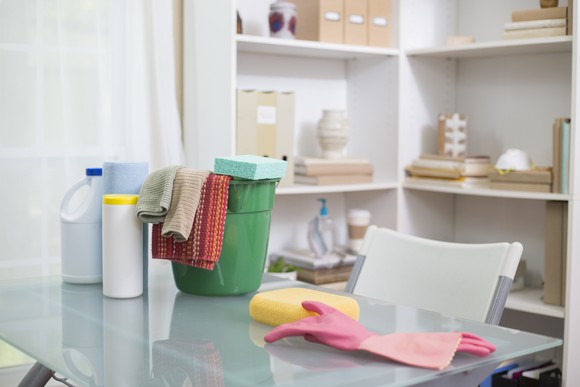 Bottles of bleach and cleaning equipment sitting on a table.