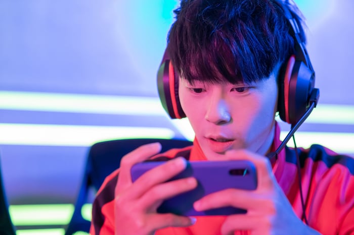 An esports player competing in a tournament by playing a game on his smartphone. 