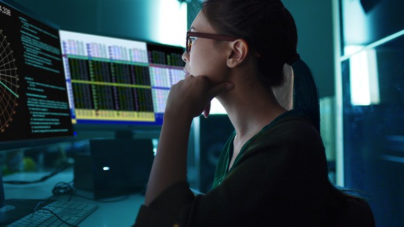 Woman studying financial market information on desktop.