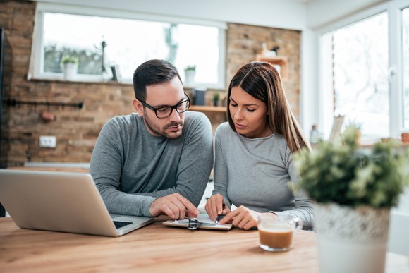Couple reviewing papers in front of laptop