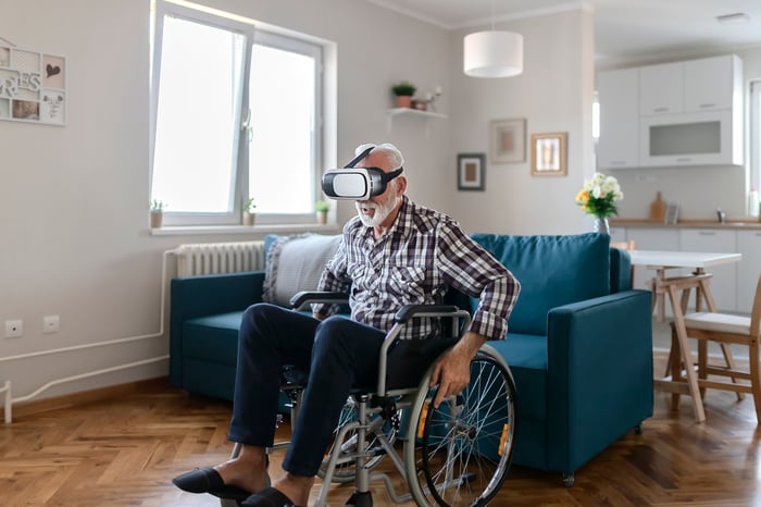 Man in wheelchair uses virtual reality device at home.