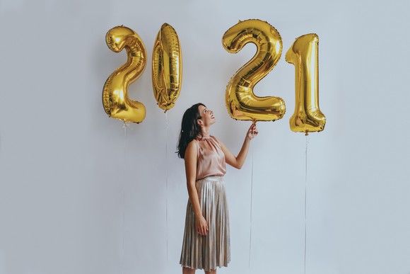 A woman looks at number balloons spelling out 2021