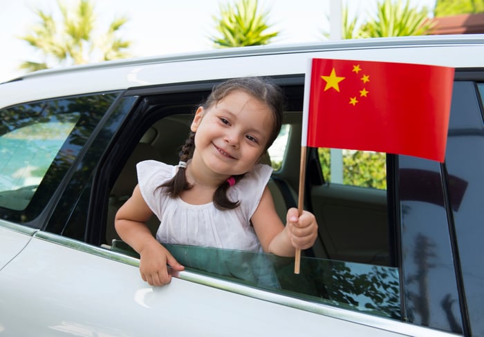 Little girl waving a Chinese flag out of a car window