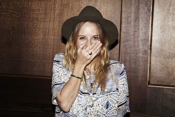 A fashionably dressed young lady laughing with her hand over her mouth