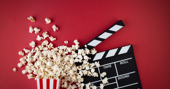 Popcorn and a movie take board against a red backdrop.