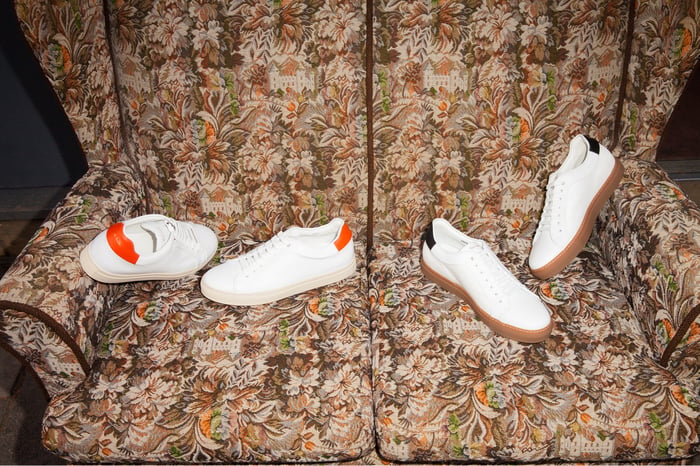 Two pairs of sneakers set against a highback chair