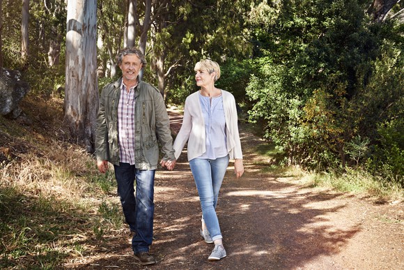 Middle-aged man and woman holding hands while walking on trail