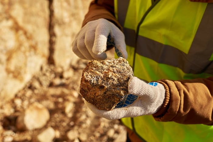 A gold miner holding up a rock.