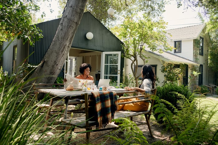 Two people working at a computer at a table in front of an Airbnb vacation rental.