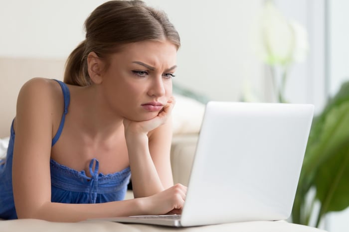 Young woman looking confused and frustrated at a laptop.