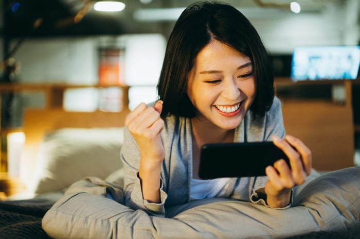 Smiling person looking at their smartphone.