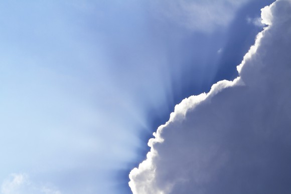 The sun peeks out behind some dark clouds.