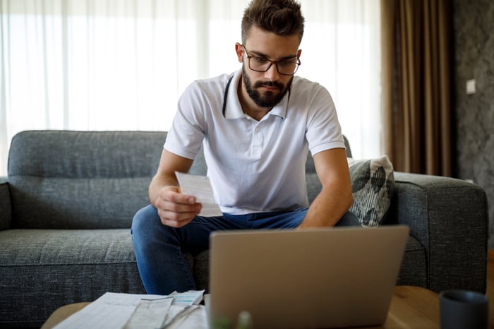 Man at laptop holding receipt