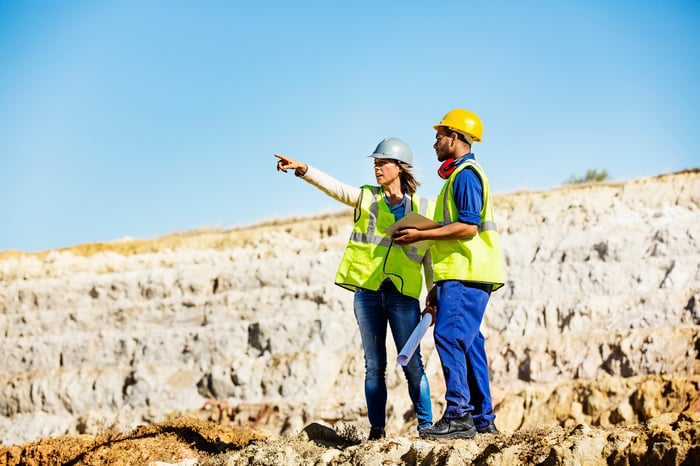 Two people in protective gear standing in an open pit mine.