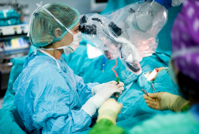 Surgeon uses a large microscope device during an operation.