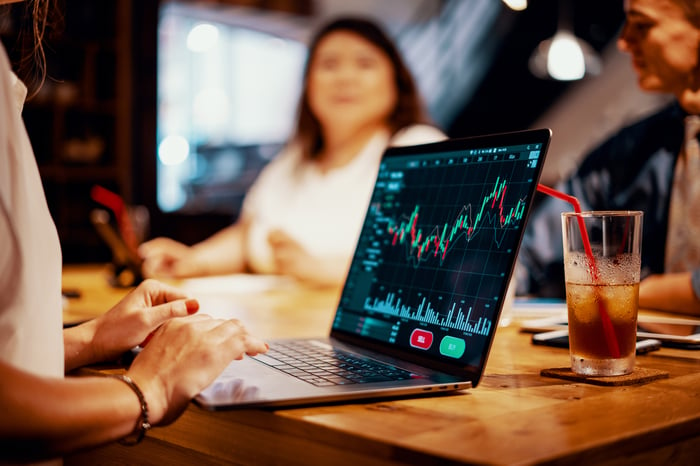 People gathered together looking at a computer screen to buy stocks.