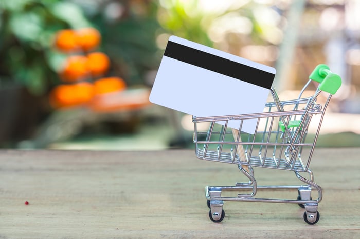 A credit card in a tiny shopping cart.