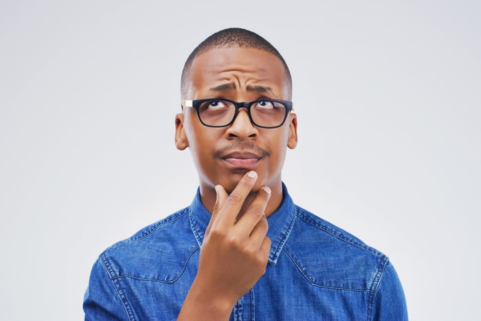 person with right hand on chin with a questioning facial expression