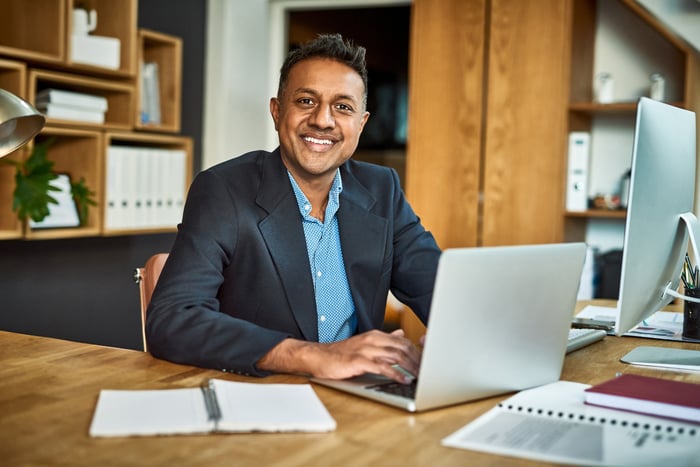 Smiling person in business suit at laptop.