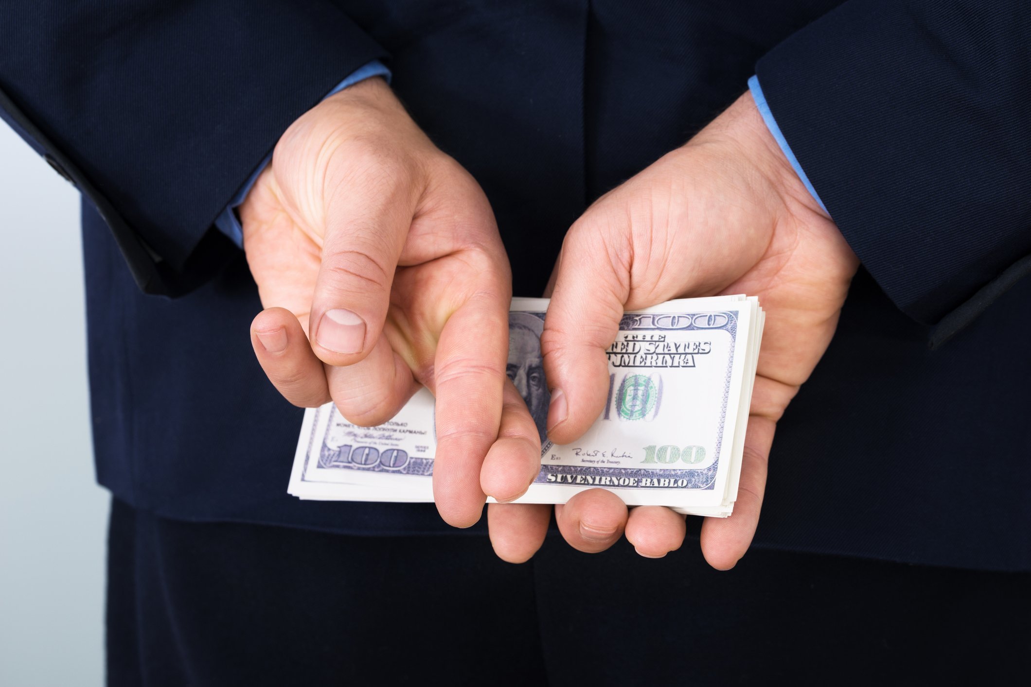 Money Behind Back Fingers Crossed Corporate Tax Getty