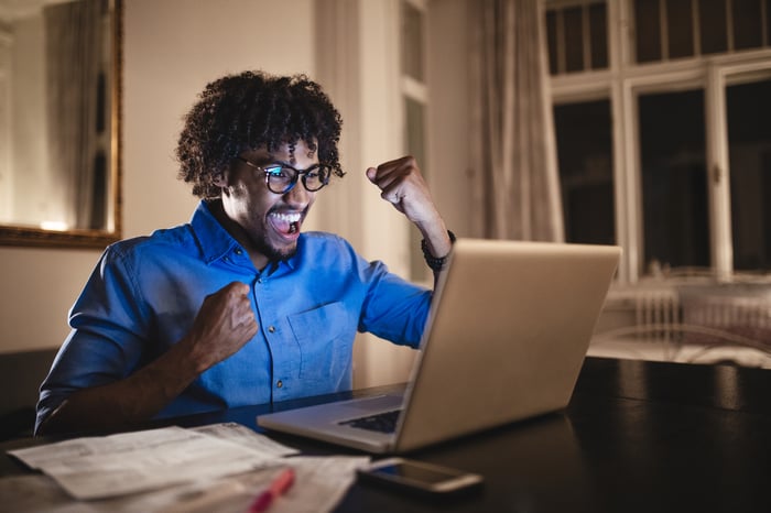 Smiling person at laptop raising arms