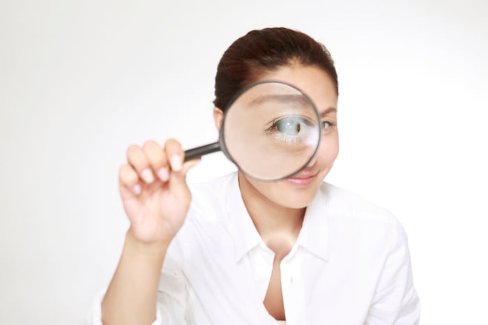 Person looking through magnifying glass