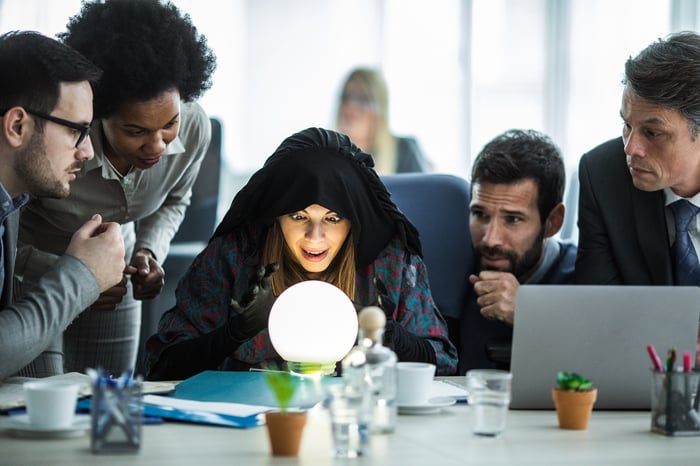 Woman looking at crystal ball at an office desk with team