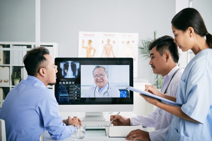 Medical staff using a desktop computer to speak virtually with a physician.