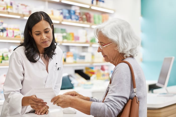 Pharmacist helps a senior at the pharmacy counter.