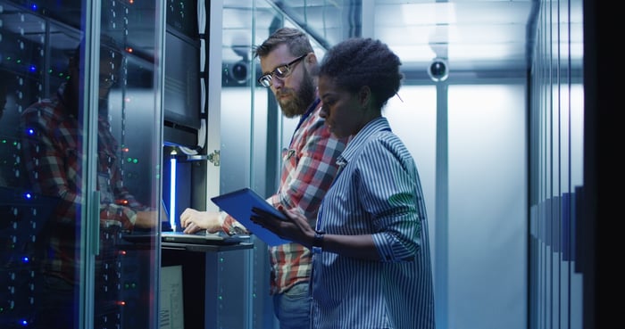 Two people working at a computer terminal in a data center.