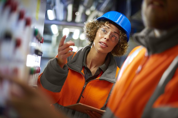 Two people working at a control panel in a boiler room at a power station.