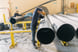 Men work on a big pipe in a factory.