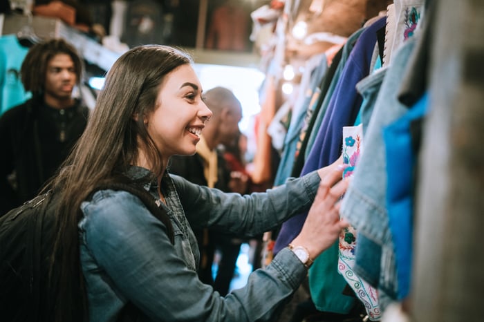 A smiling group of young adults have fun shopping for retro and vintage clothing.