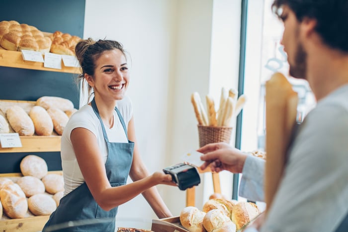 A person paying with a credit card at a bakery.