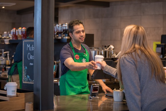 A Starbucks barista serving coffee to a customer.