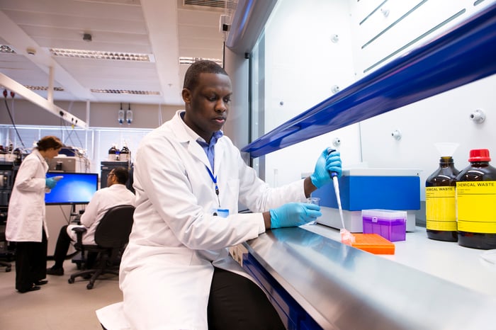 A lab researcher using a pipette to transfer liquid samples to a test tray. 