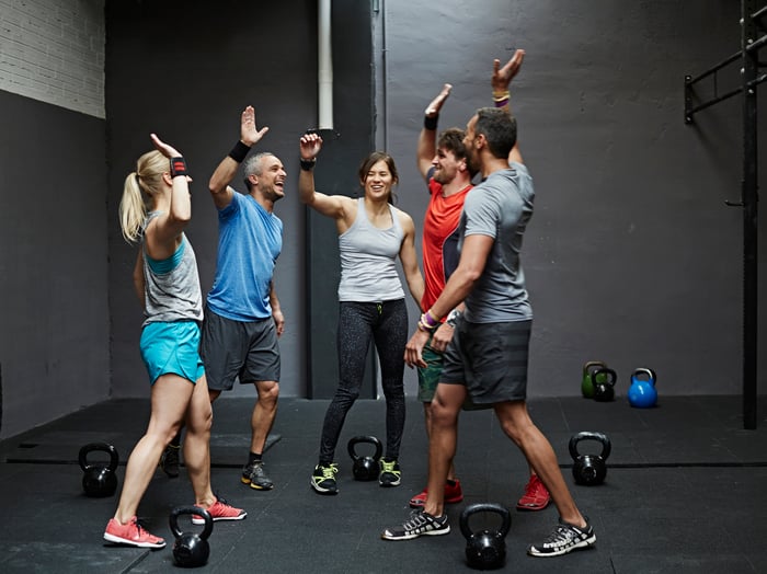 A group of people in workout clothing high-fiving each other.